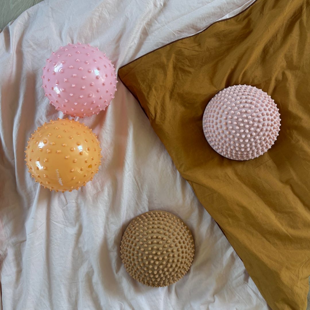 to sansebolde i rosa og orange samt to lyse sansesten fra Find that Hippo, ligger på dyne, hos Nordic Simply