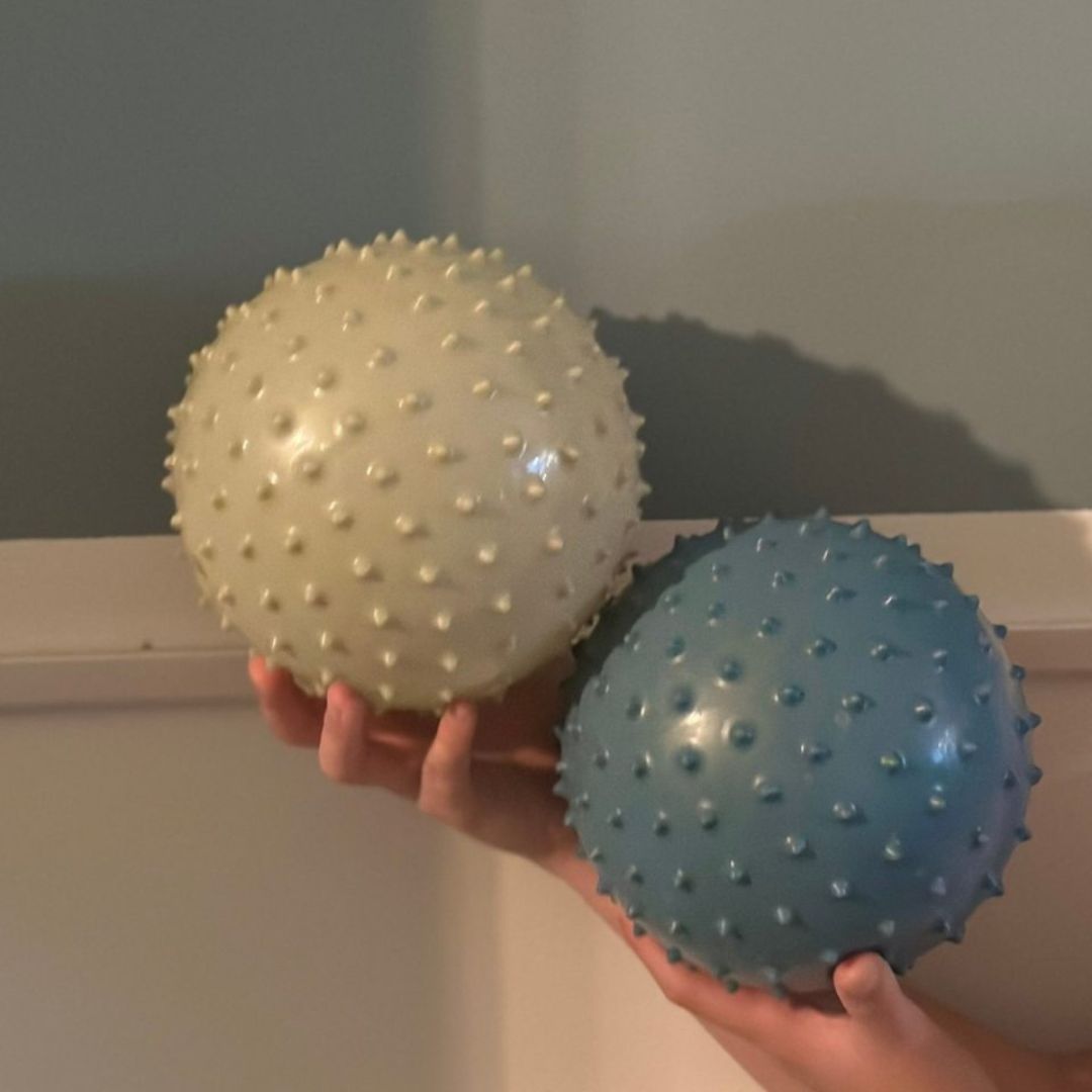 hænder med to sansebolde med knopper i blå og khaki, fra Find that Hippo fås hos Nordic Simply