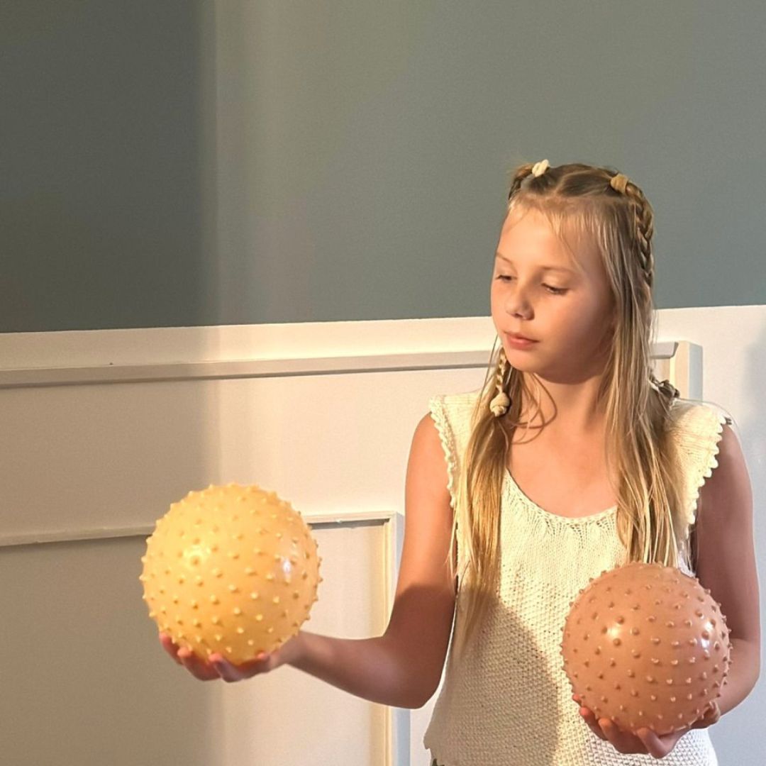 pige med to sansebolde med knopper i gul og rosa, fra Find that Hippo fås hos Nordic Simply