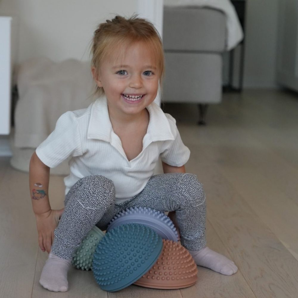 pige leger i stue med fire sansesten i mørke pastelfarver fra Find that Hippo fås hos Nordic Simply