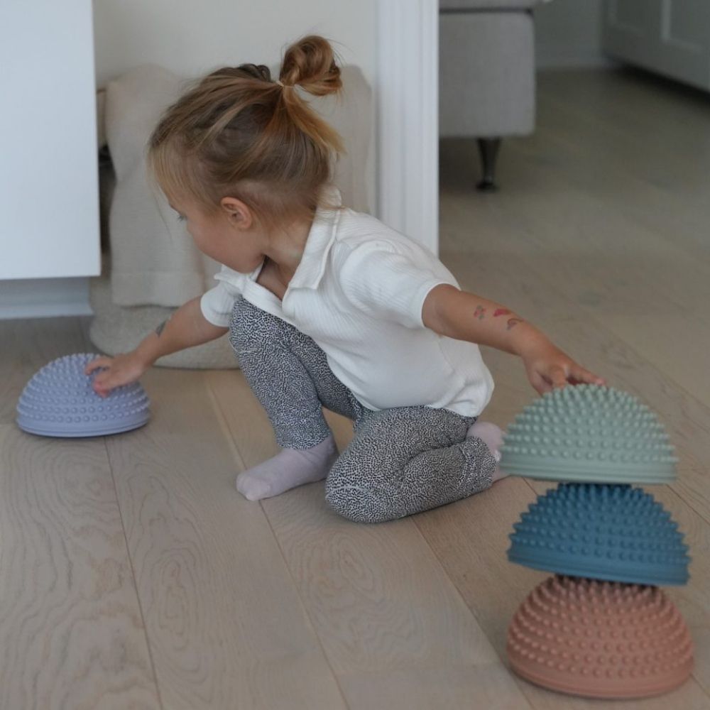 pige leger i stue med sansesten i mørke pastelfarver fra Find that Hippo fås hos Nordic Simply