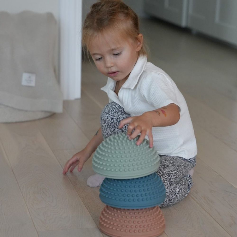 pige leger i stue og stabler sansesten i mørke pastelfarver fra Find that Hippo fås hos Nordic Simply