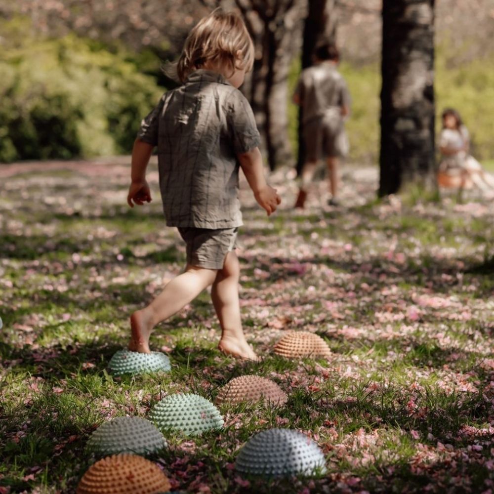 Barn går på bane af sansesten i pastelfarver udendørs i skovbund, sansesten fra Find that Hippo fås hos Nordic Simply