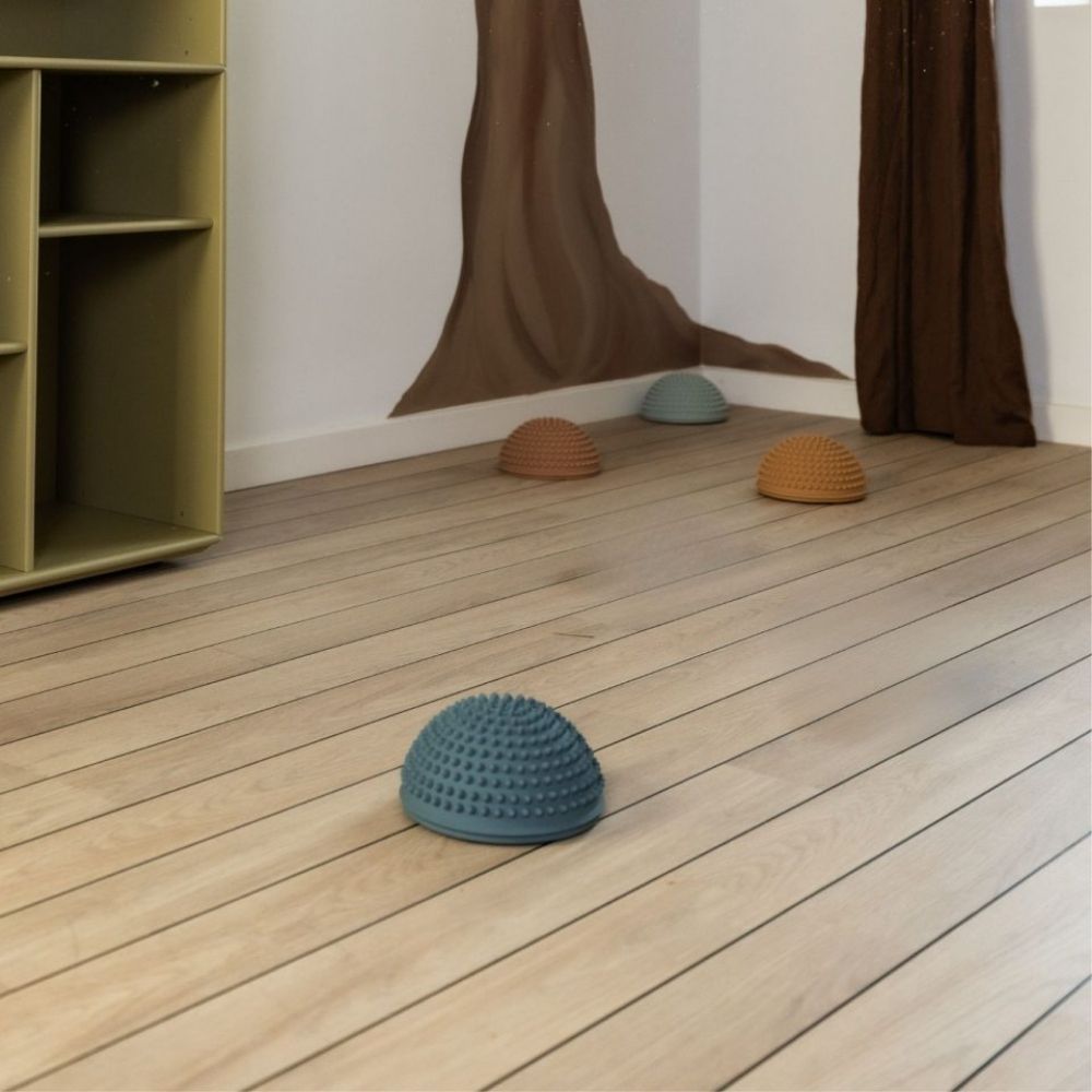 4 sansesten med knopper i mørke pastelfarver ligger indendørs på trægulv, fås hos Nordic Simply