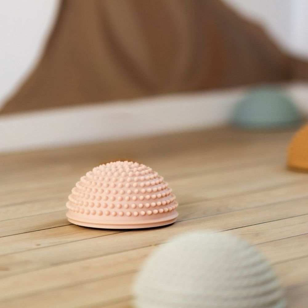 rosa sansesten med knopper til børn fra Find That Hippo, ligger på trægulv