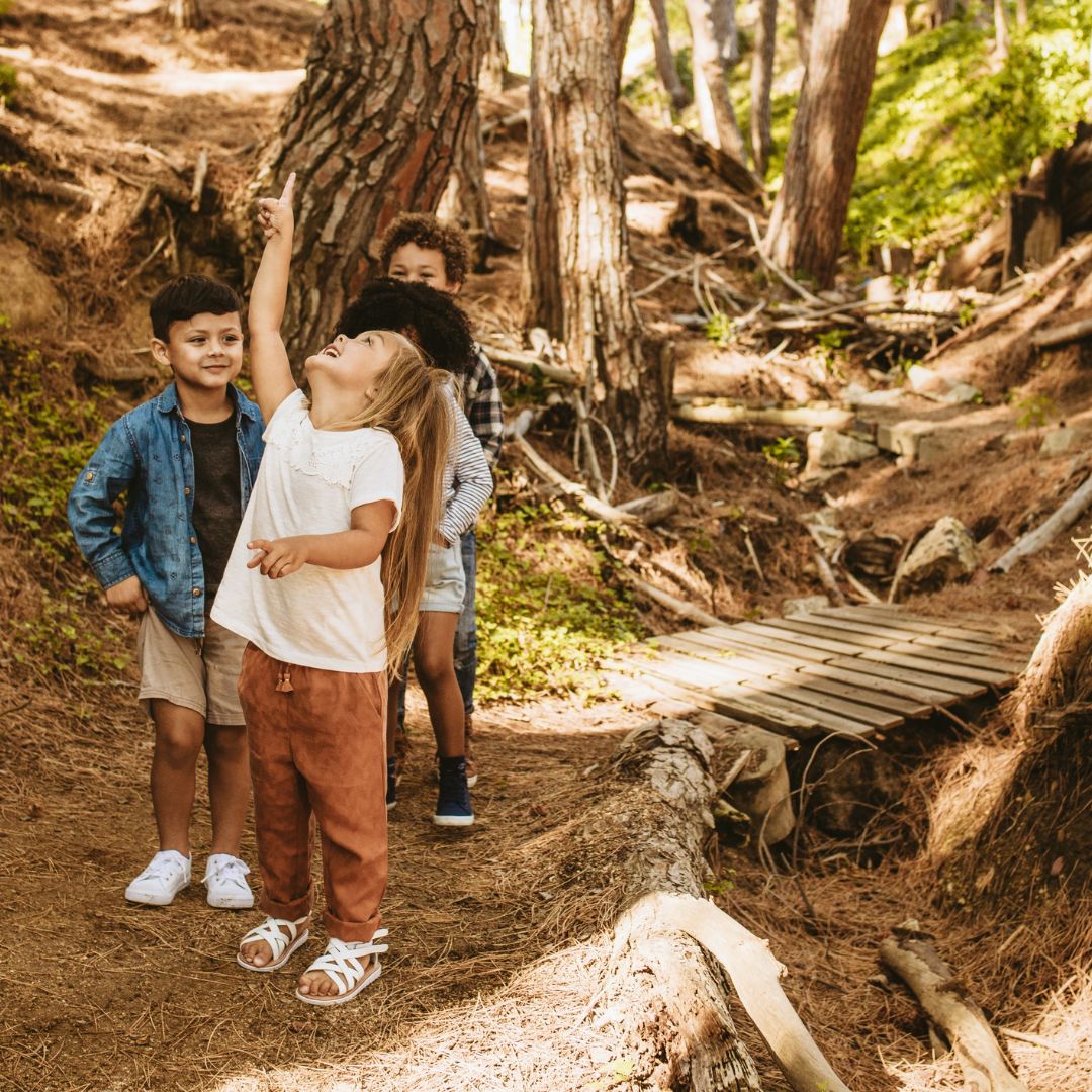 Glade børn leder efter poster på skattejagt i skoven med print-selv skattejagt fra Nordic Simply