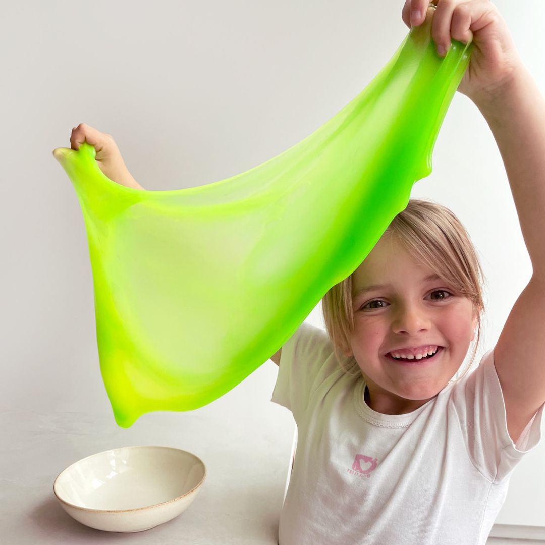 Barn holder stor klat slim i neon fra Tuban, gul og grøn