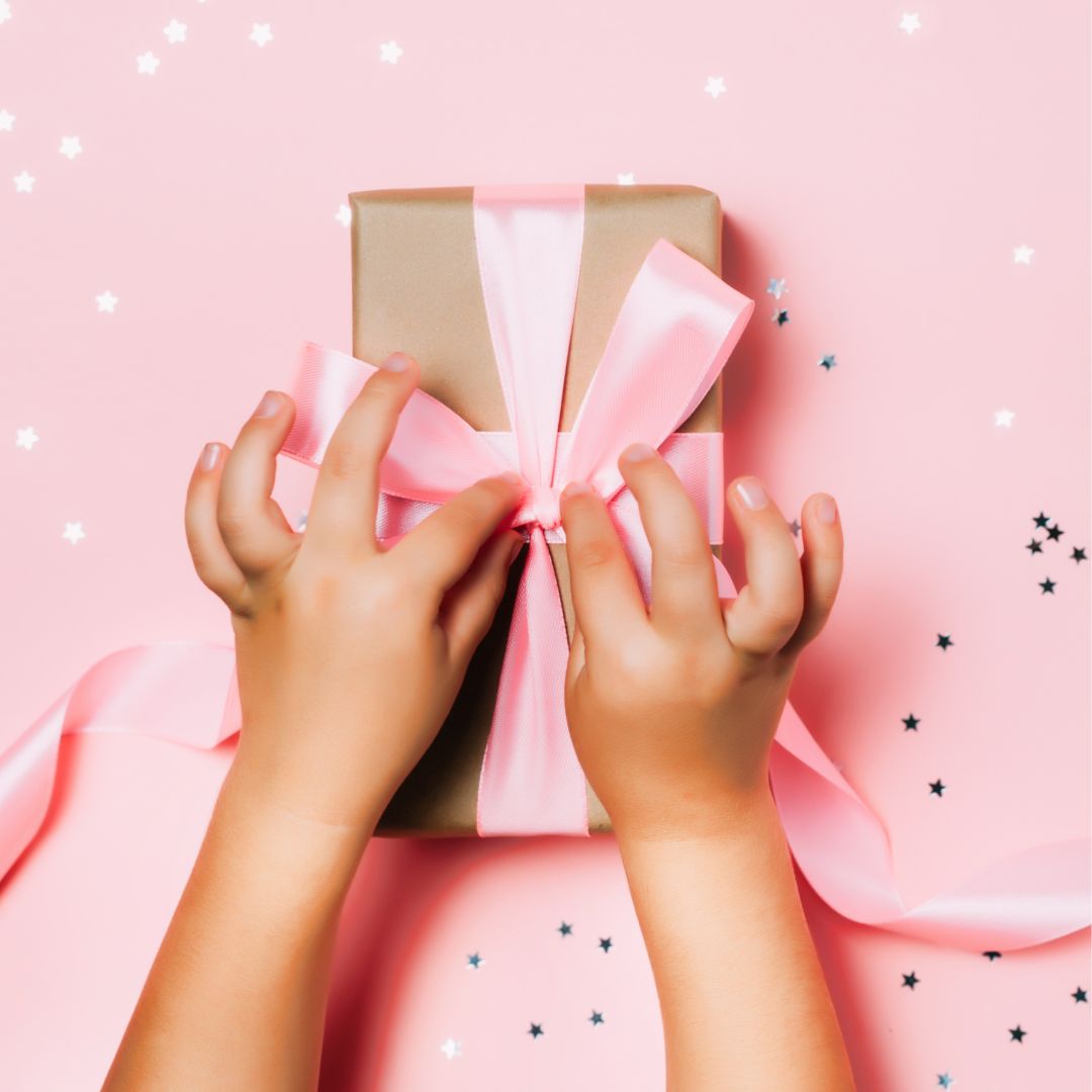 Hænder åbner gave med rosa sløjfe til fødselsdag
