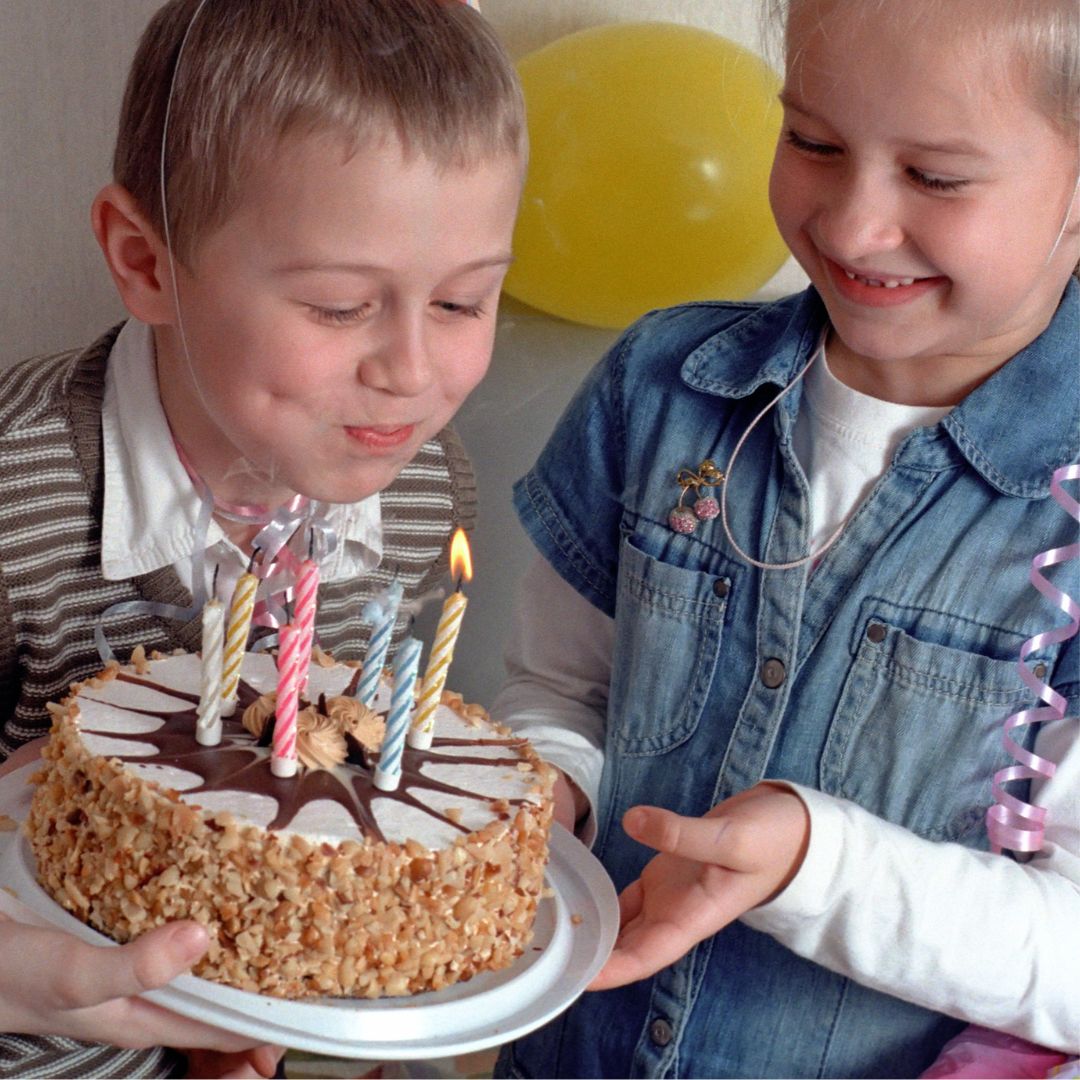 Dreng puster lys ud på lagkage til fødselsdag, kasse med blandede gaver til børnefødselsdag 6-9 år fås hos Nordic Simply