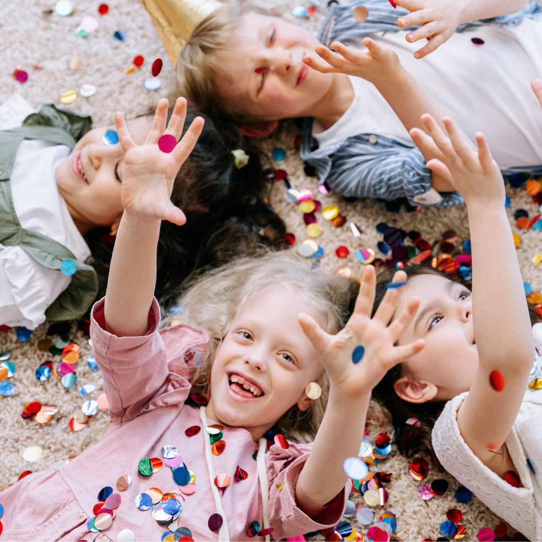 Børnligger på gulv og ler med masser af´konfetti til børnefødselsdag
