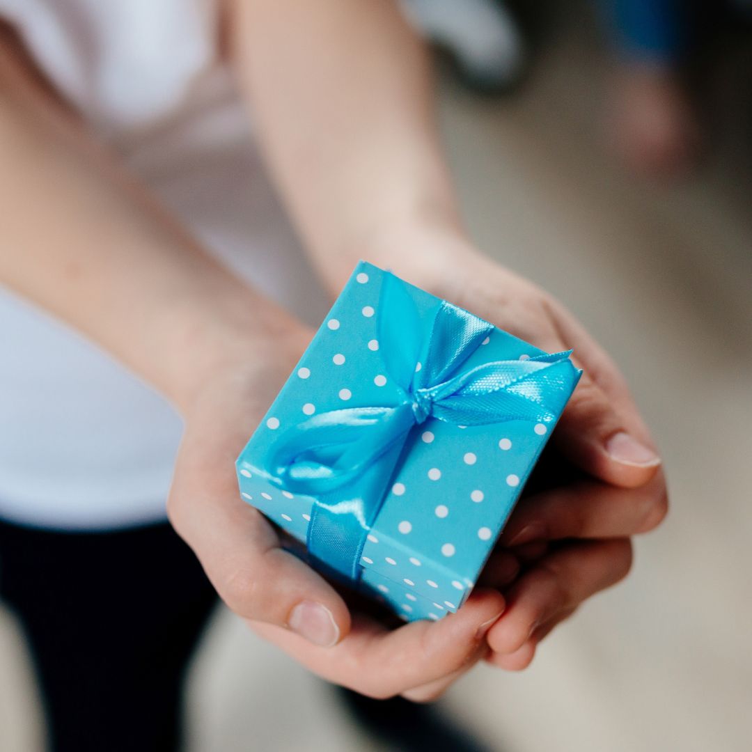 Hænder holder lille gave til fødselsdag, 20 gaver i kasse fås hos Nordic Simply