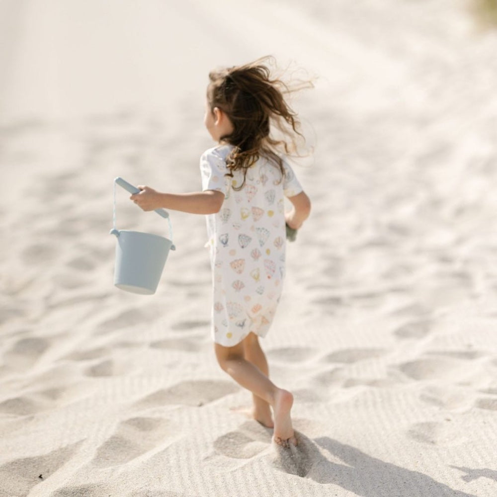 Barn leger på strand med blå spand i silikone, kan foldes, god til ferie og rejser
