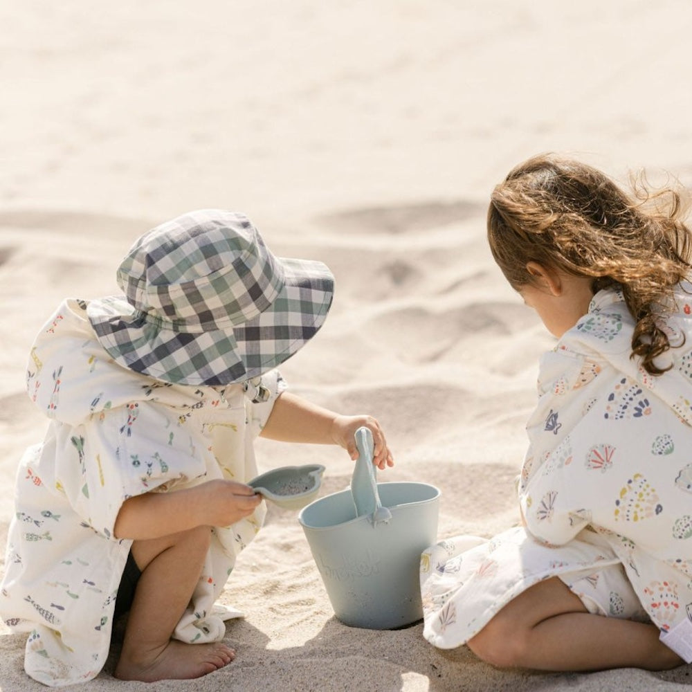 Børn leger på strand med blå spand i silikone, kan foldes, god til ferie og rejser