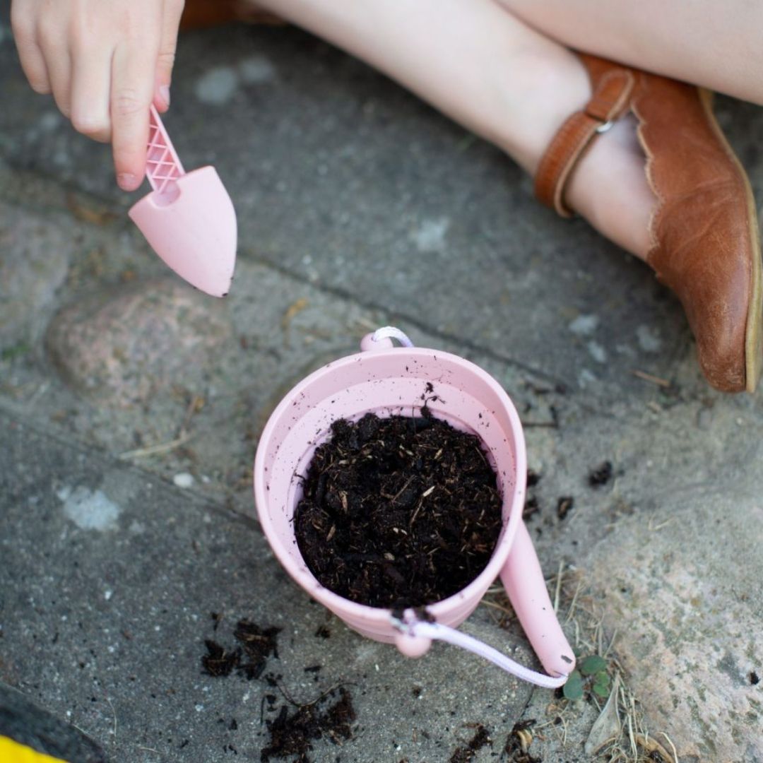 Llille rosa spand fra Scrunch, med jord i, spanden kan foldes og er let at tage med på ferie, fås hos Nordic Simply