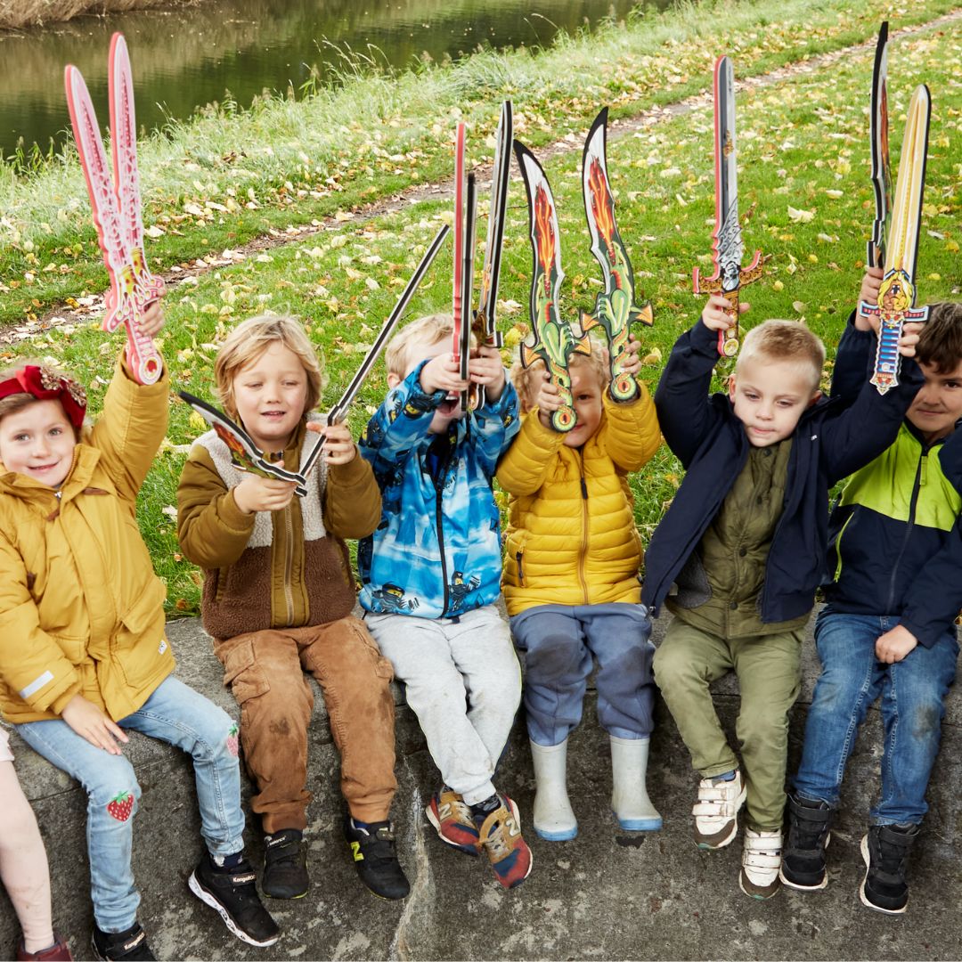 Børn sidder udendørs med flotte sværd i skum, blandt andet prinse-sværd fra danske Liontouch