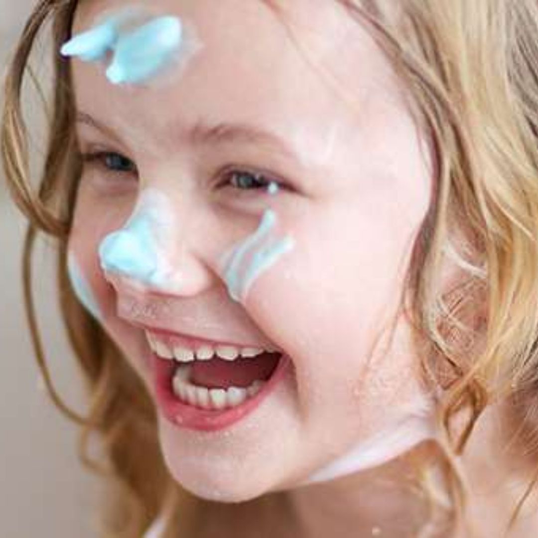 Pige ler med skum i ansigtet fra Tinti tryllekugle til badet, fås hos Nordic Simply