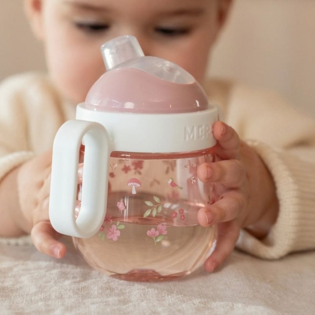 barn undersøger rosa og hvid tudkop med håndtag, koppen er spildfri, fra Mepal x Little Dutch.