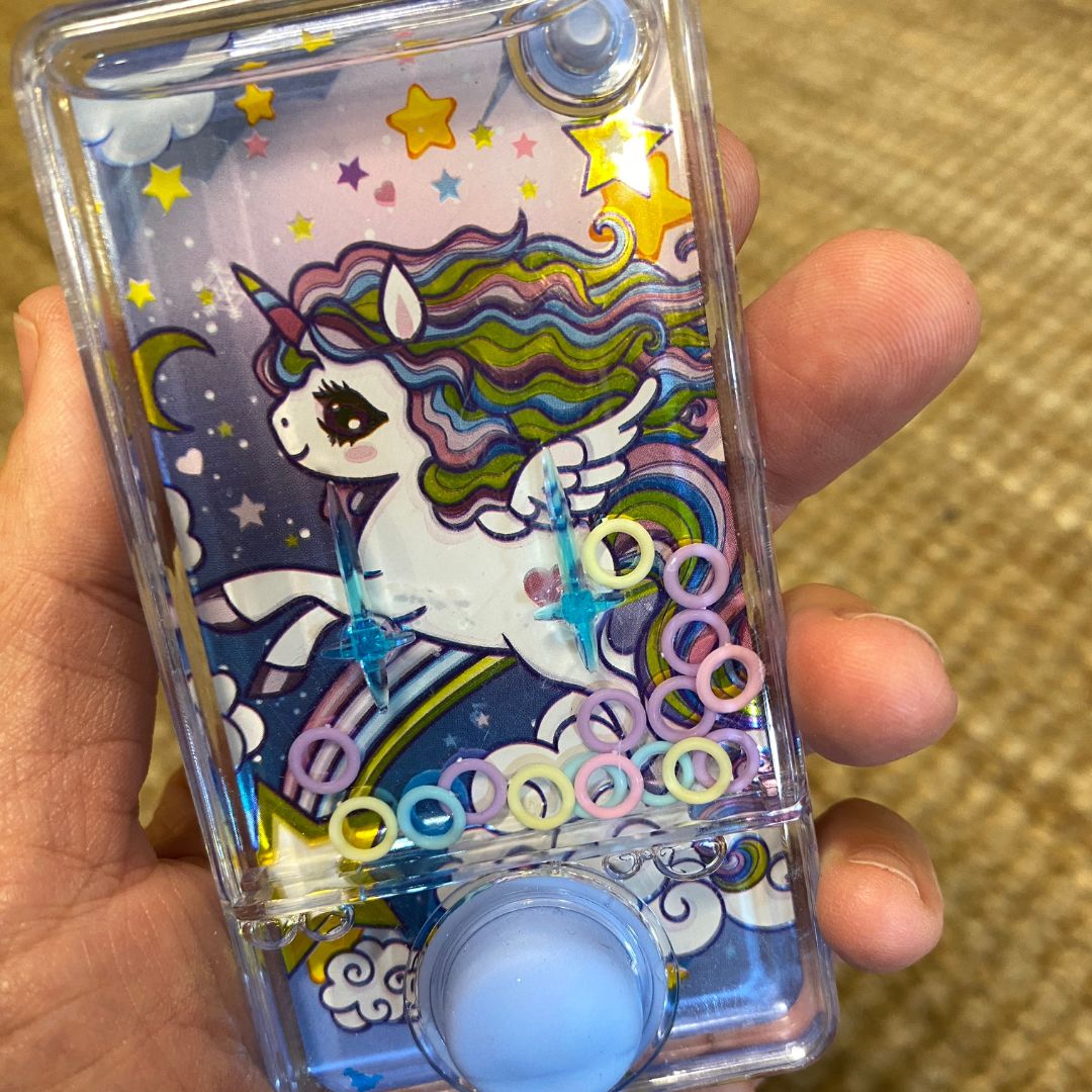 Hånd holder vandspil med enhjørning, fint lille spil til rejser, bilture og flyrejse