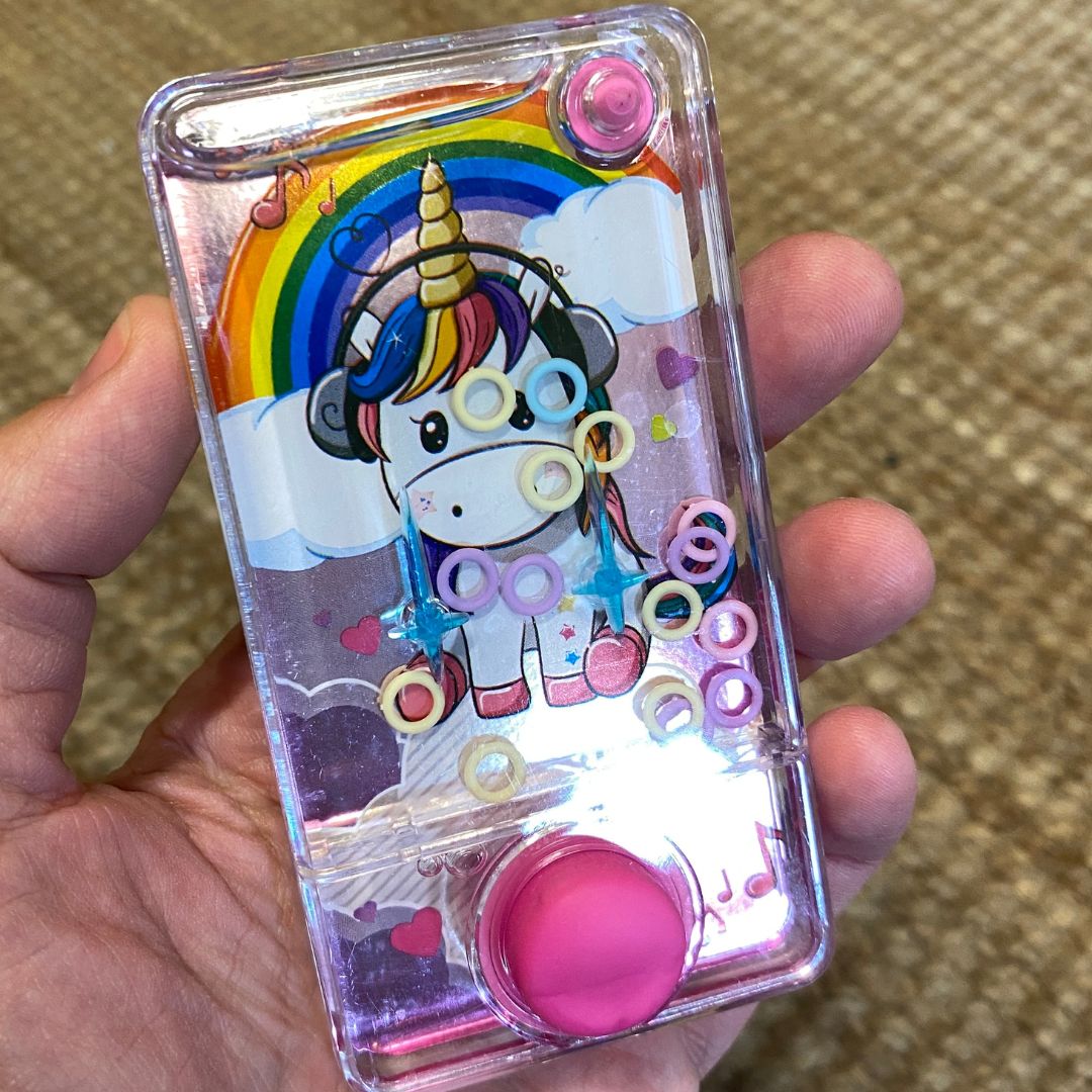 Hånd holder rosa enhjørning vandspil, fint lille spil til rejser, bilture og flyrejse