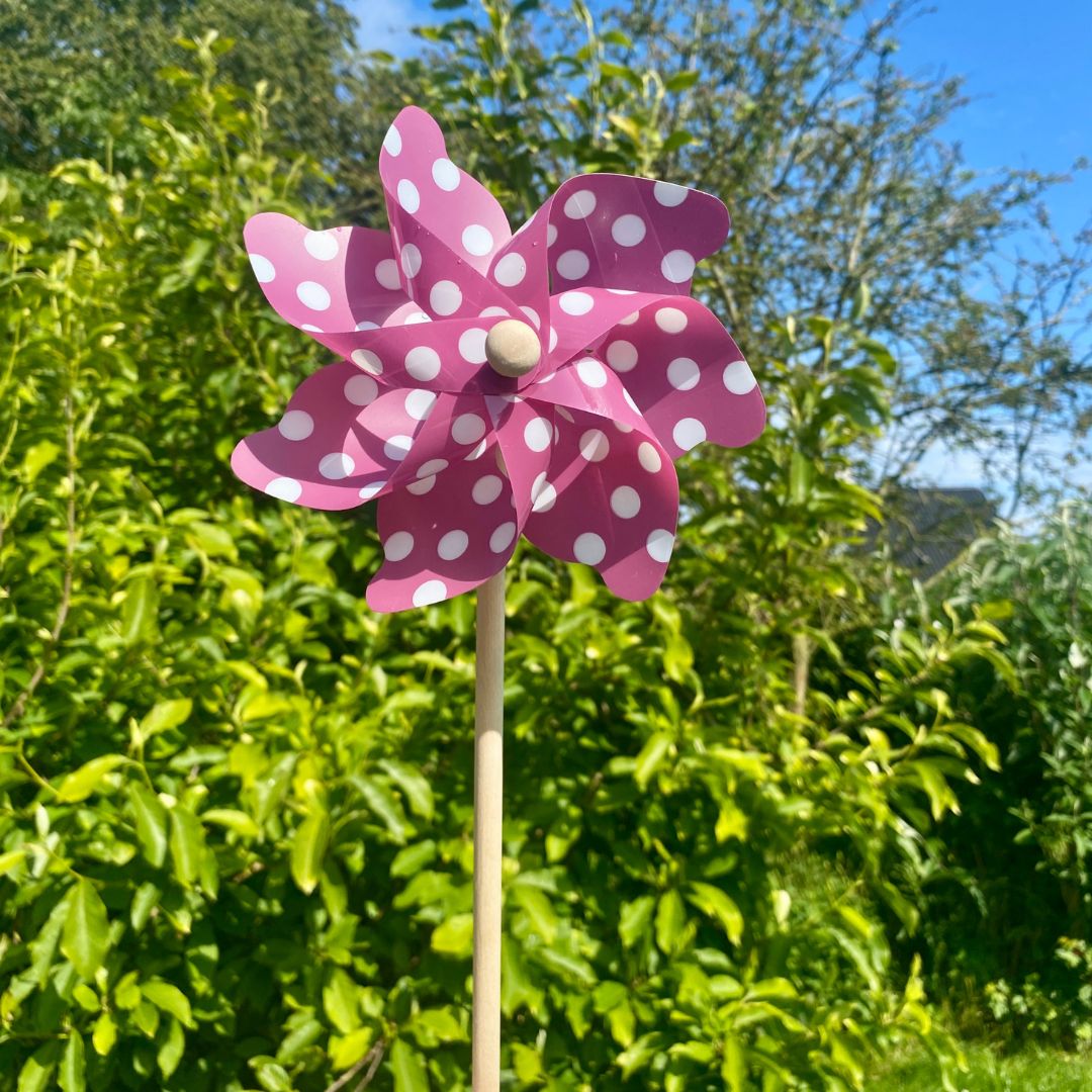Lilla vindmølle med hvide polkaprikker, set udendørs med grønne planter i baggrunden, fra Magni, fås hos Nordic Simply