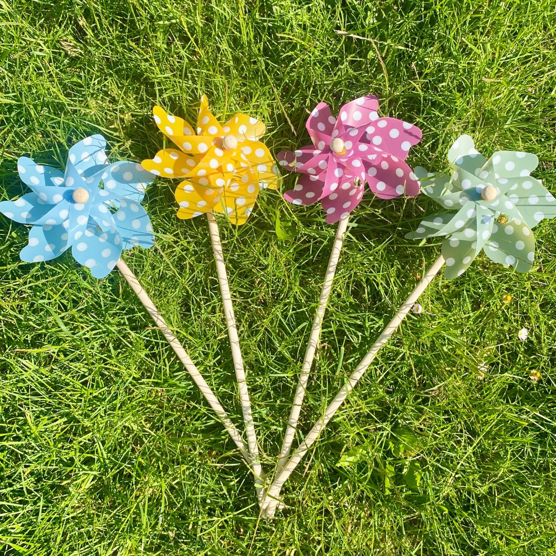 4 vindmøller i blå, gul, lilla og grøn med hvide polkaprikker, ligger i en vifte på græs, fra Magni, fås hos Nordic Simply