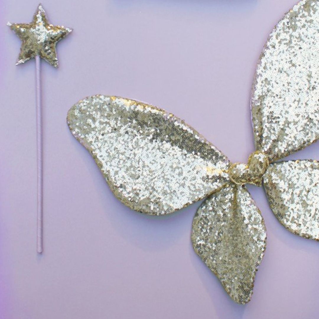 Tryllestav i guld og og vinger i guld og glitter, ligger på lilla baggrund, perfekt udklædning som sommerfugl til børn fra 3 år og op fra Mimi & Lula fås hos Nordic Simply