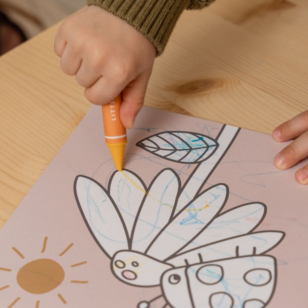 Hånd tegner med orange voksfarve i tegnebog, begge dele fra Little Dutch, fås hos Nordic Simply
