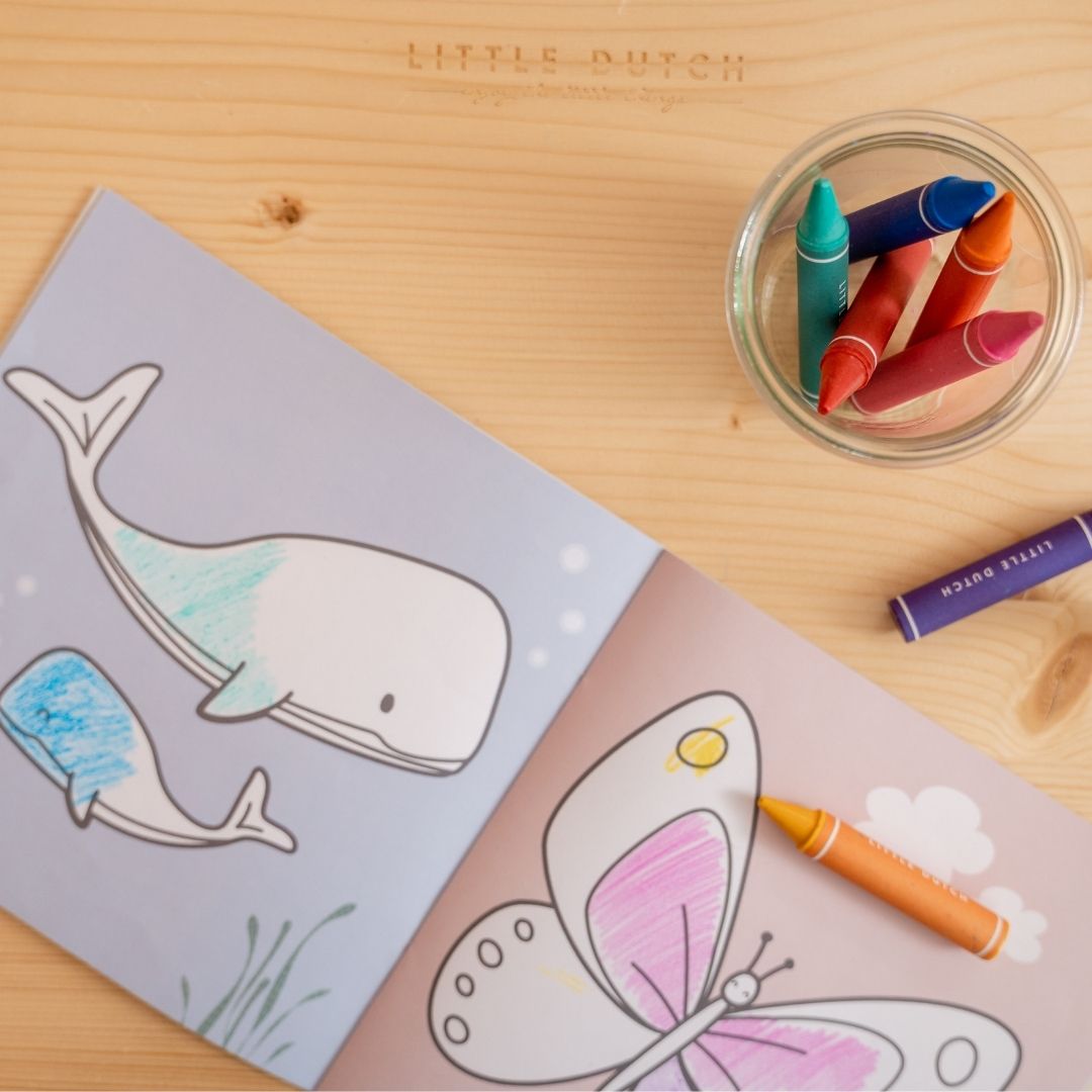 Glas med voksfarver i et glas står ved tegnebog fra Little Dutch, begge dele fås hos Nordic Simply