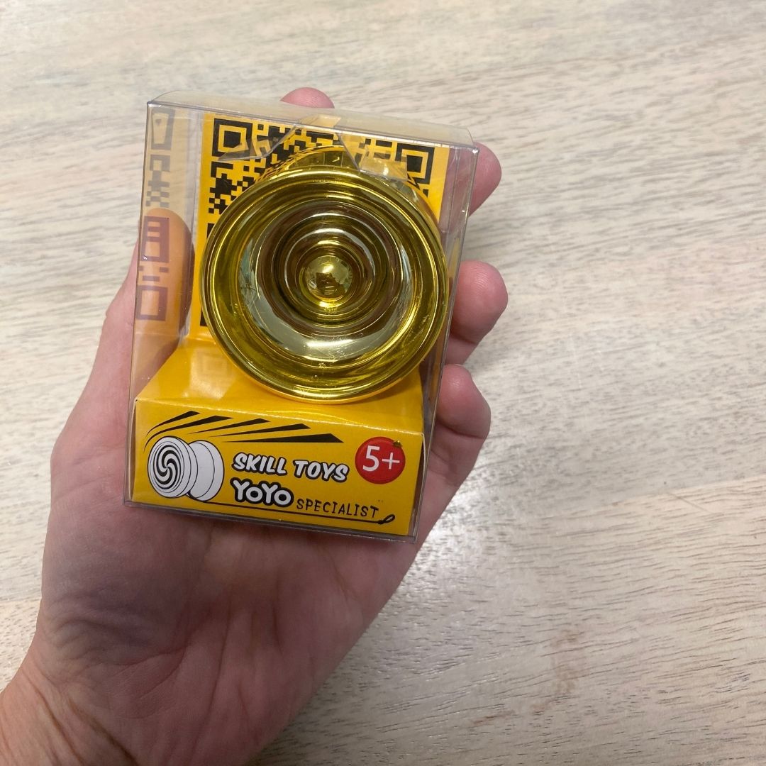 Hånd holder guldfarvet yoyo i æske til aktiv leg ude og inde for børn