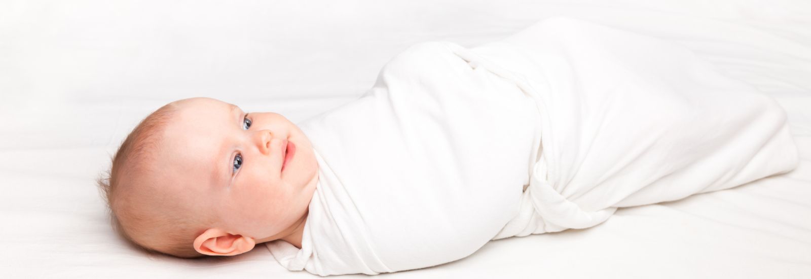 baby ligger i hvidt svøb