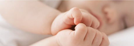 baby sover med hænder liggende afslappet foran ansigtet 