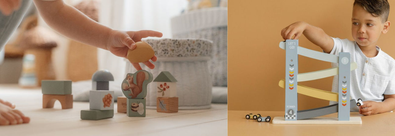 barnehånd bygger med lyseblå byggekloser i træ på gulv i lyst rum, dreng leger med blå rampe med biler, julegaver til dreng 2 år hos Nordic Simply 
