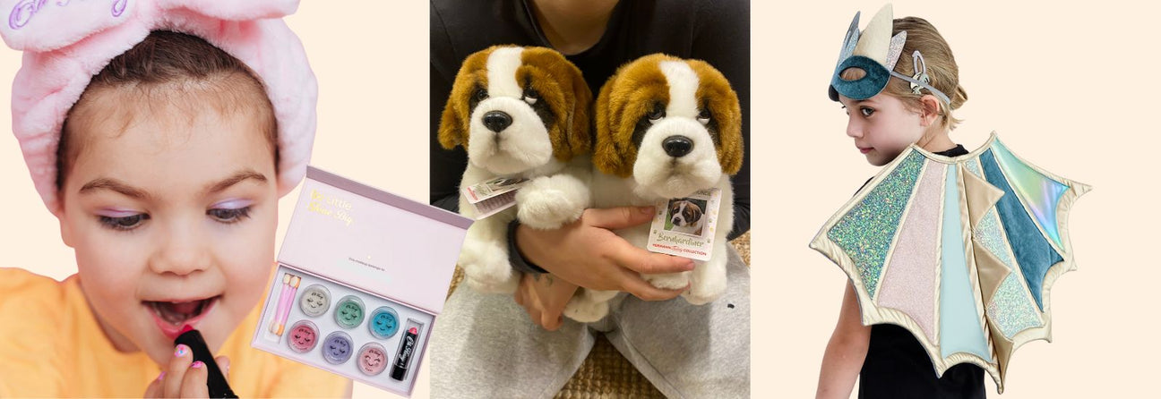 pige med børne-makeup læbestift, barn holder to bamsehunde sankt bernhardt bamser, pige med pastelfarvede dragevinger og dragemaske, julegaver til pige 5 år hos Nordic Simply