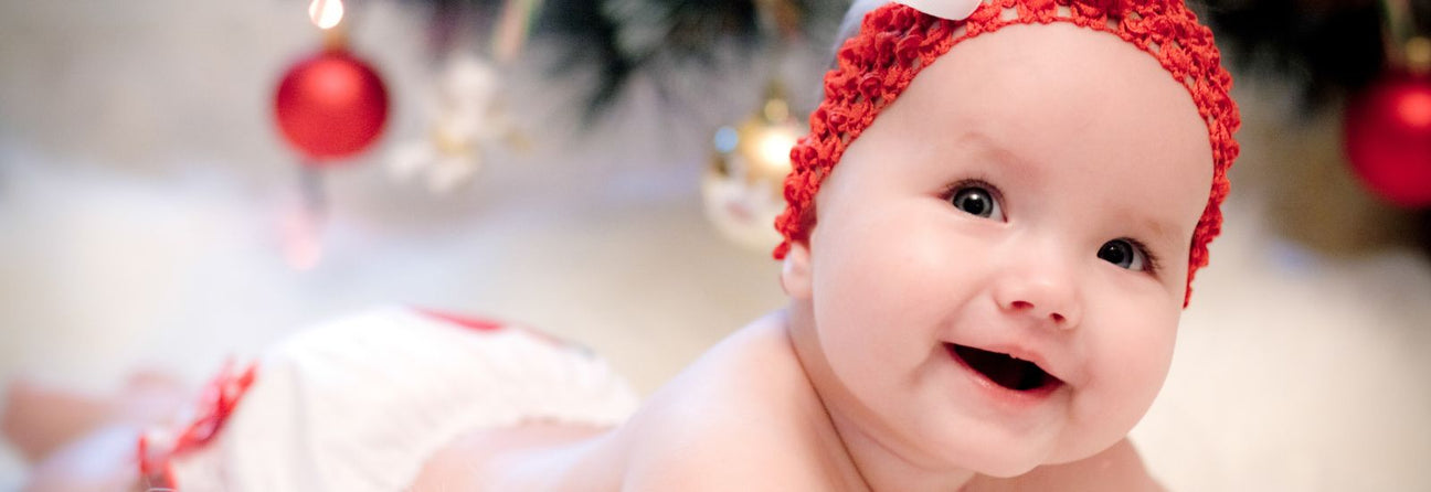 baby pige 6-9 mdr ligger med nissehue på. Find adventsgaver til baby pige 6 til 9 måneder hos Nordic Simply