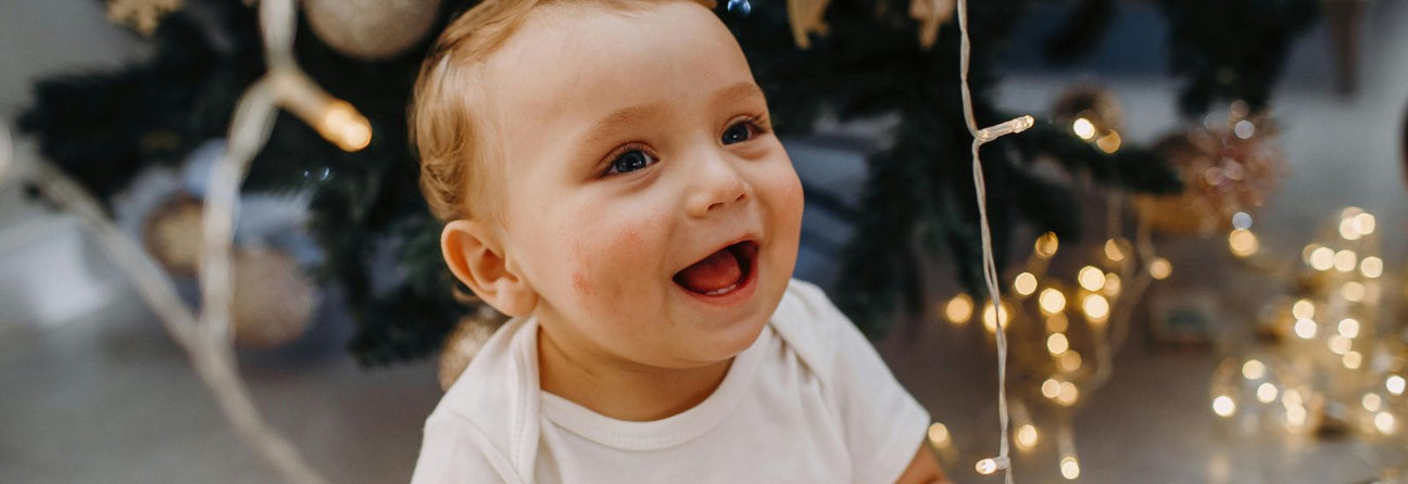 baby ved juletræ med gaver, find adventsgaver til baby hos Nordic Simply