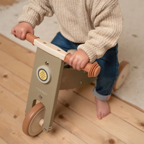 Barn på olivenfarvet træbalancecykel fra Little Dutch, udvikler balance og koordination indendørs.