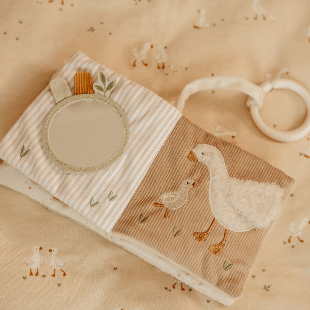 Blød beige aktivitetsbog fra Little Dutch med motiver af gås og kanin samt masser at opleve for baby, her set slået op på sider med spejl og gås med gæsling, fås hos Nordic Simply
