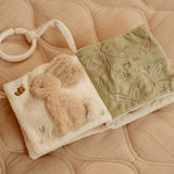 Blød beige aktivitetsbog fra Little Dutch med motiver af gås og kanin samt masser at opleve for baby, her set slået op på sider med blød kanin og grønne blade, fås hos Nordic Simply