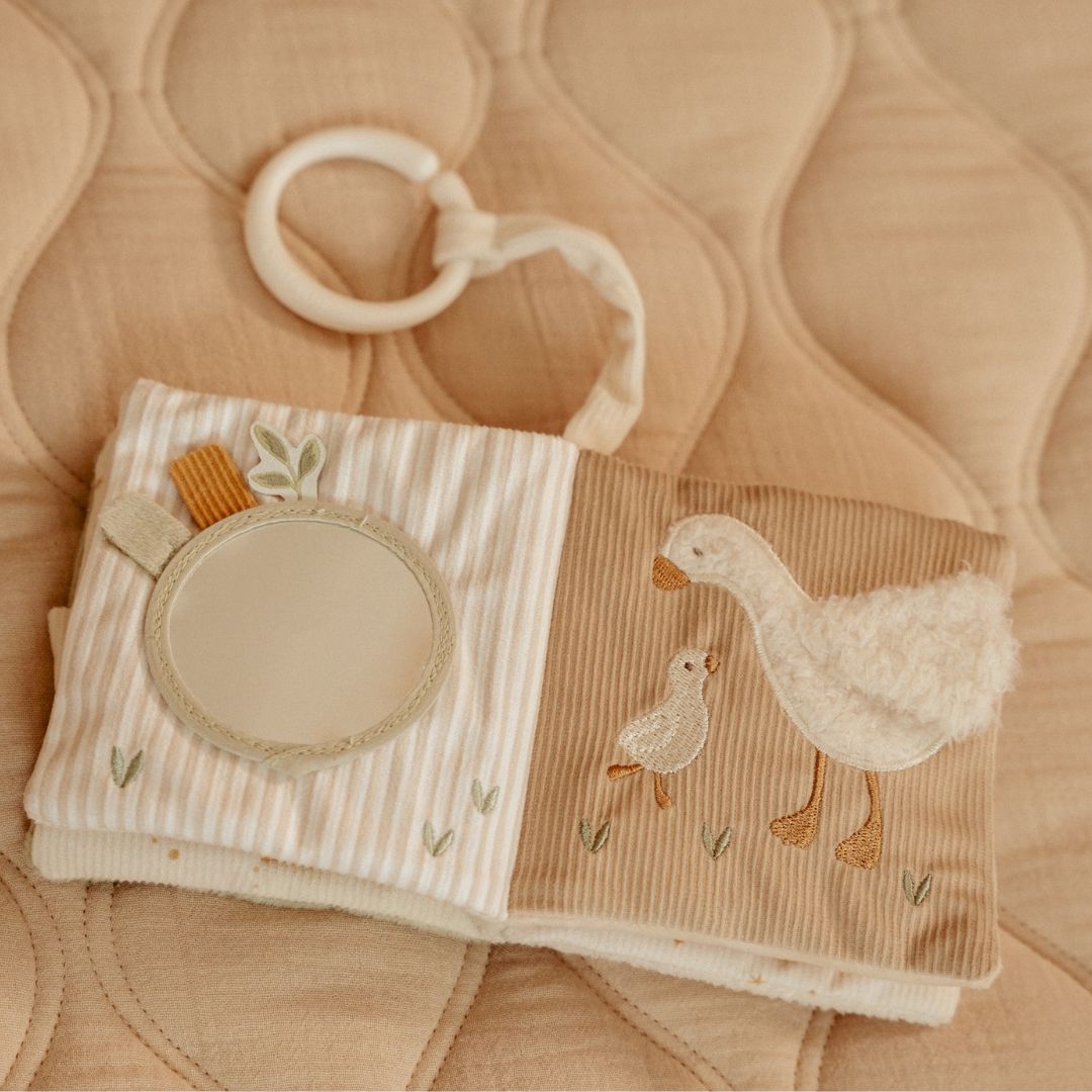 Blød beige aktivitetsbog fra Little Dutch med motiver af gås og kanin samt masser at opleve for baby, her set på lysebrun baggrund, slået op på sider med spejl og gås med gæsling, fås hos Nordic Simply