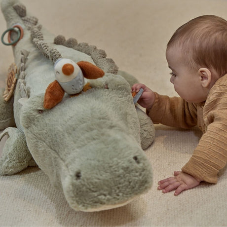 baby på gulvtæppe undersøger stor lysegrøn krokodille bamse med aktiviteter, en aktivitetsbamse med masser at udforske fra nyfødt og op, Little Dutch Safari kollektion.