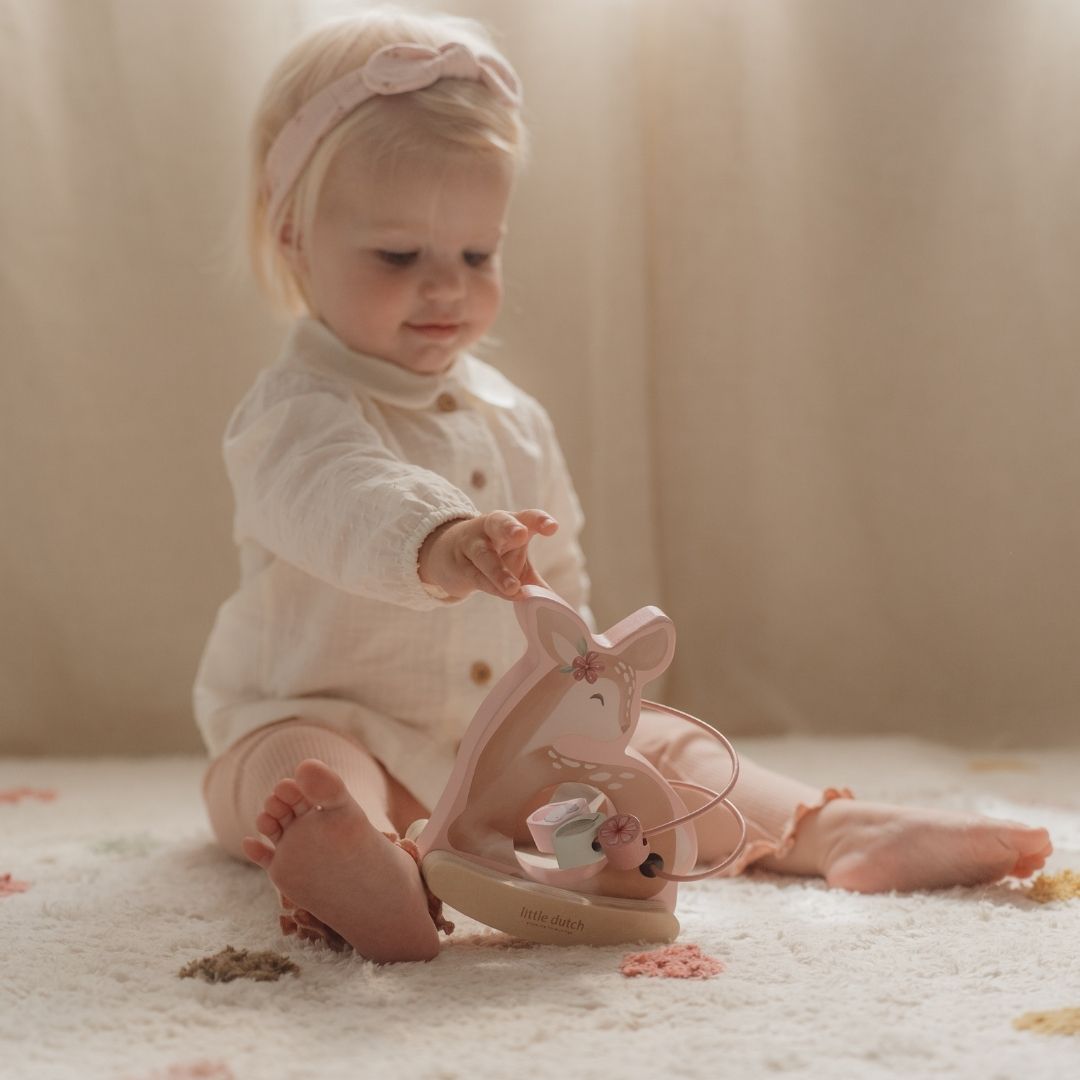 Aktivitetsdyr rosa: Barn på gulv leger med charmerende rosa rådyr i træ med sjove perler til leg og motorik.