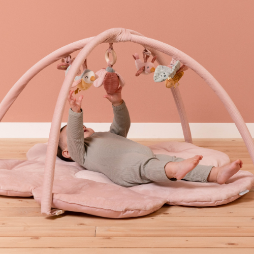 Baby playing on pink flower-shaped activity mat with toys, designed in light pink with soft velvet arches, stimulating senses.