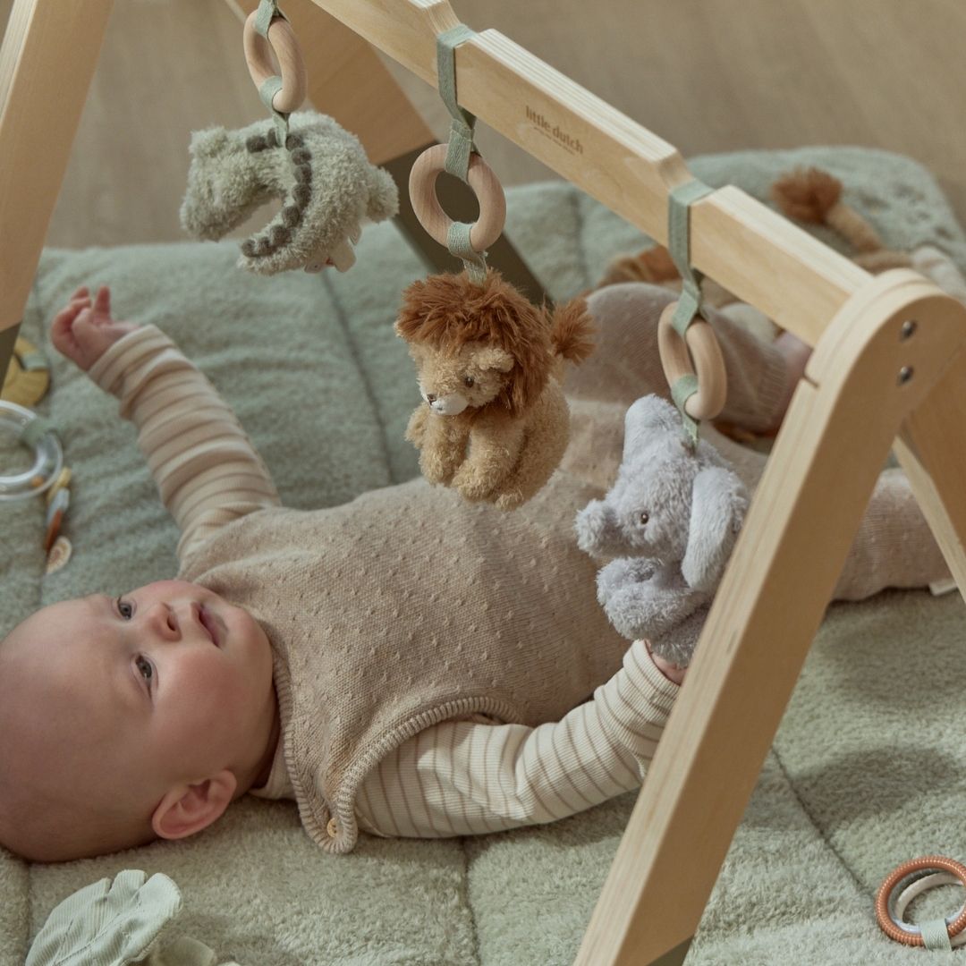 Baby under aktivitetsstativ med safaridyr, babygym i træ med grønne ben og tre dyr at udforske: elefant, løve og krokodille. Fra Little Dutch.
