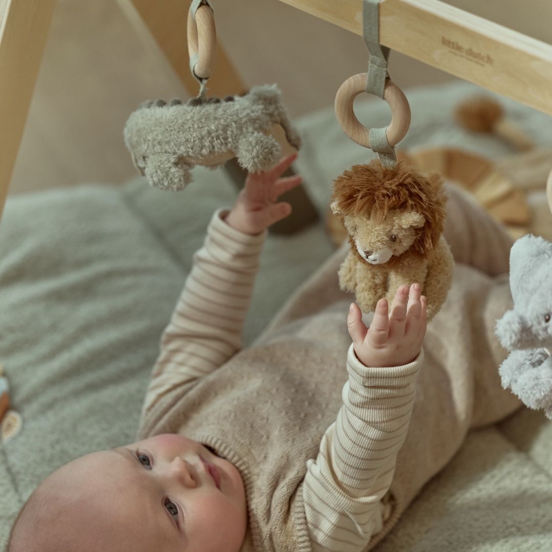 baby undersøger løve på aktivitetsstativ til med safaridyr, babygym i træ med grønne ben og tre dyr at udforske: elefant, løve og krokodille. Fra Little Dutch.