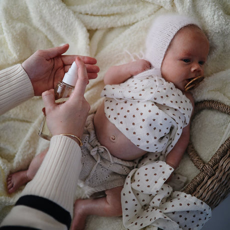Mushie babyolie 145 mL parfumefri, Svanemærket, produceret i Danmark. Her ses baby og voksen, der er klar til at smøre baby ind.