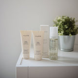 Mushie babyolie 145 mL parfumefri, Svanemærket, produceret i Danmark. Her set på bord med andre produkter i samme serie