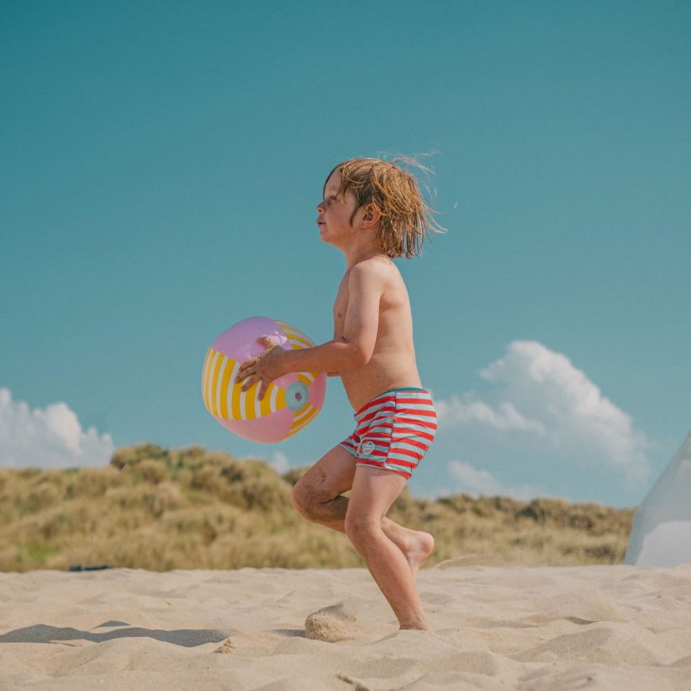 Dreng leger på strand med rosa badebold. Godkendt fra +1 år.