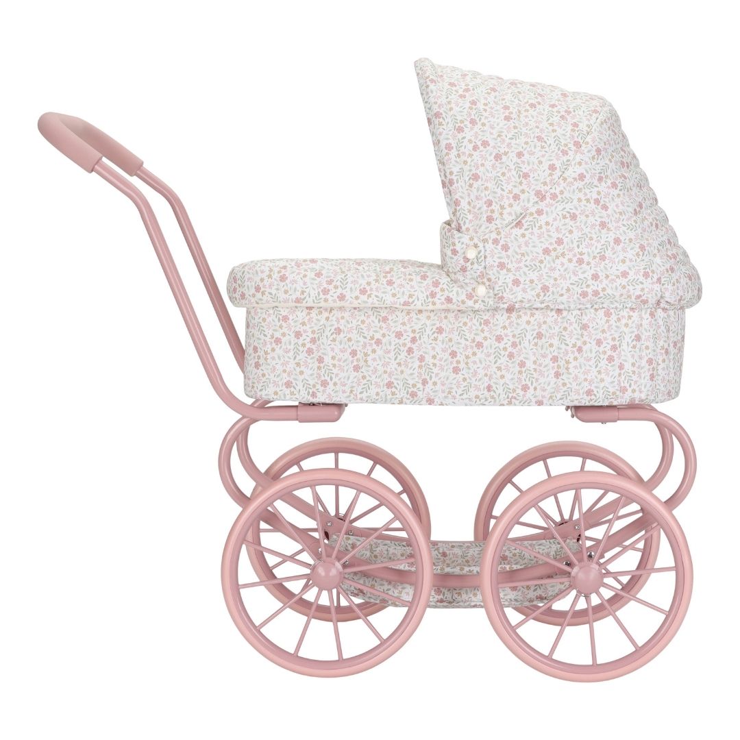 Pige ude med barnevogn til dukke, set fra siden. Med rosa stel og hvidt betræk med små blomster. Flot dukkevogn til ture med dukke både ude og inde, fra Little Dutch, fås hos Nordic Simply