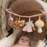 Baby i barnevogn, ligger og ser på barnevognskæde i rosa med rådyr og søde dyr fra skoven.