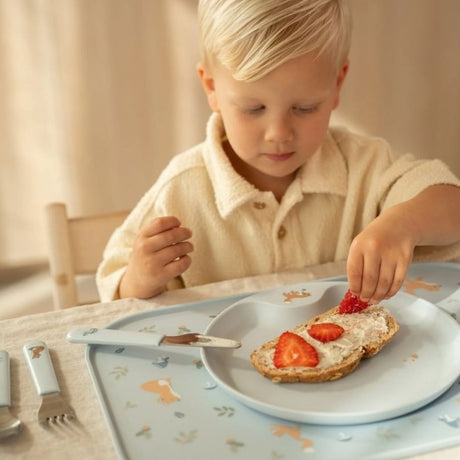 barn ved bord med blå børnebestiksæt i rustfrit stål med godt greb for små hænder fra Mepal x Little Dutch